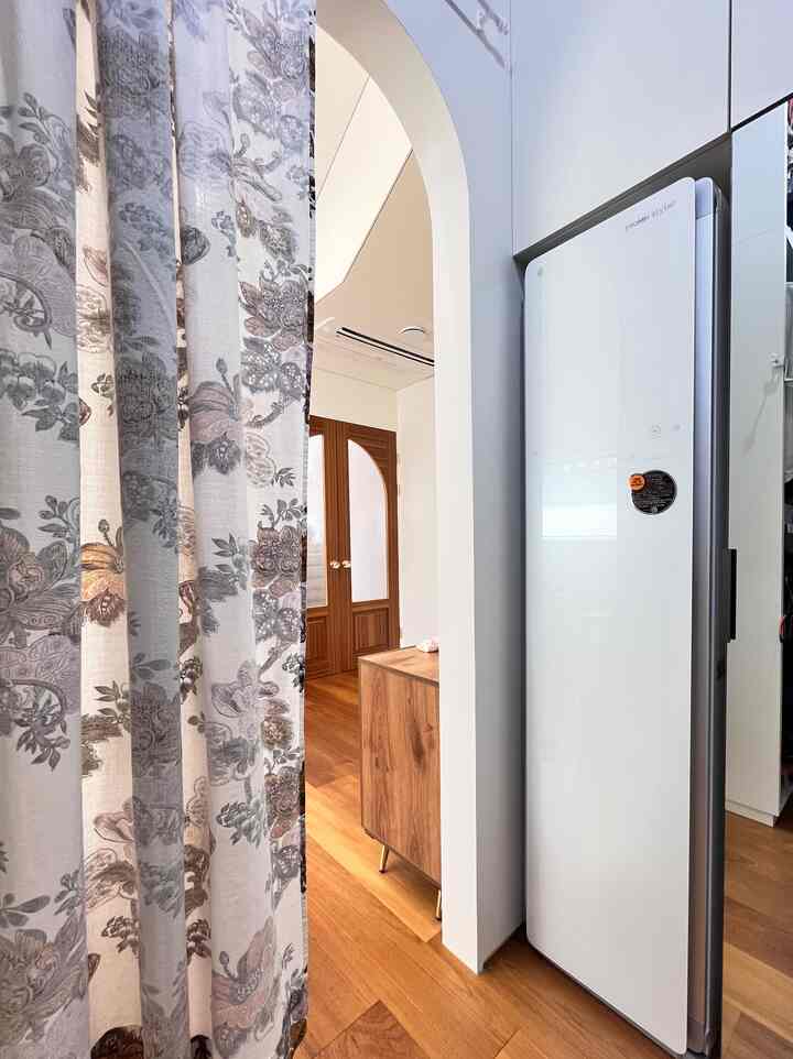 ホワイトとブラウンのウォークインクローゼット、スタイラーとビルトイン収納が調和した実用的な空間