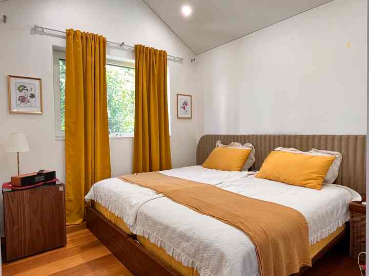 明るく華やかなゴールドとホワイトの色調の寝室、カーテンとベッドが配置された雰囲気のあるインテリア