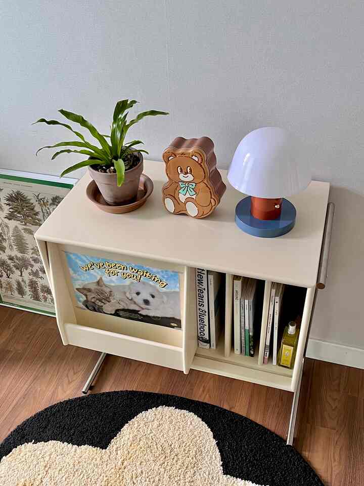 ベージュ色のLPキャビネットの上に植物、クマのインテリアアイテム、白いテーブルランプが置かれた整ったインテリア空間