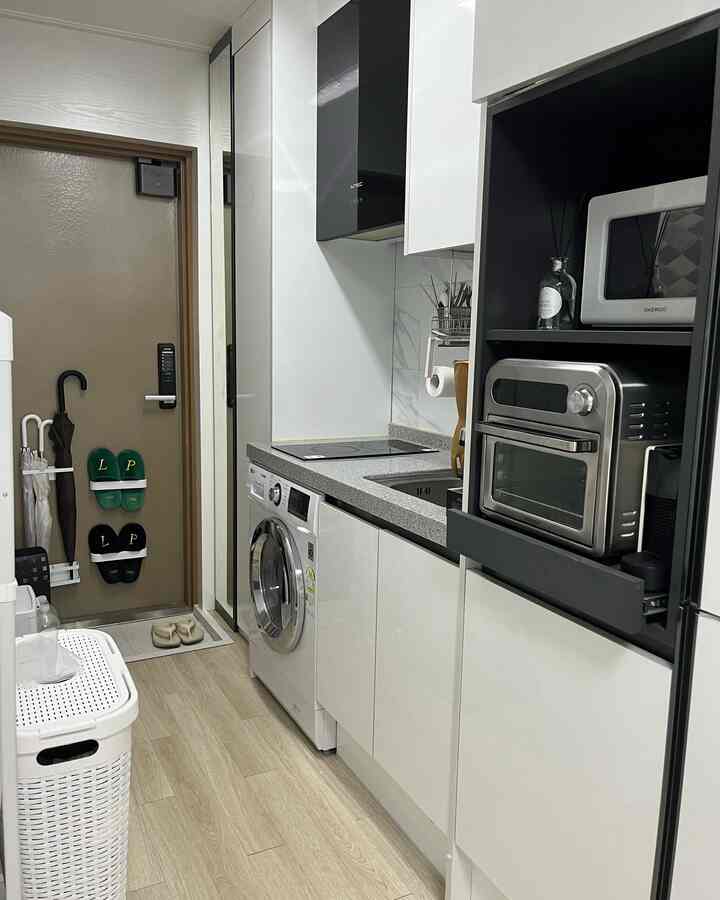 清潔感のあるホワイトを基調とした狭いモダンキッチン、洗練されたキャビネットと多様なキッチン家電が配置された実用的な空間