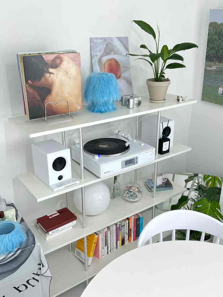 白を基調としたミッドセンチュリーモダンのダイニングルーム、シンプルなバウハウスのキャビネットとレコードプレーヤーが配置された印象的な空間