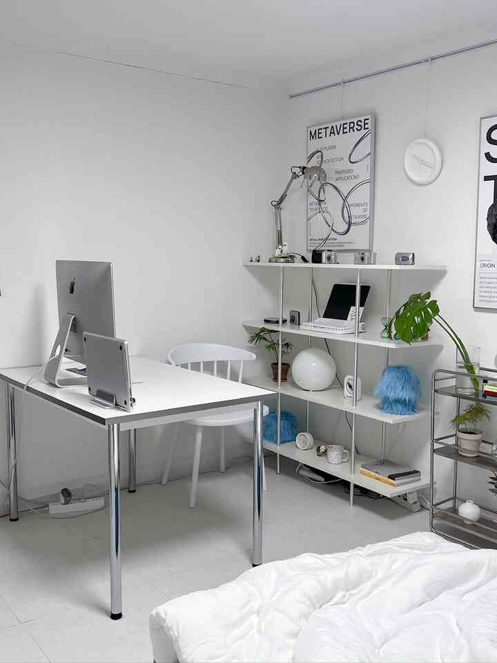 白とスチールの組み合わせのモダンミニマルな寝室兼ホームオフィス、整然としたデスクと本棚が配置された空間