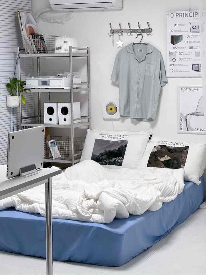 白と青のトーンの寝室、中央にベッドと北欧風ポスターが配置された清潔で居心地の良い空間