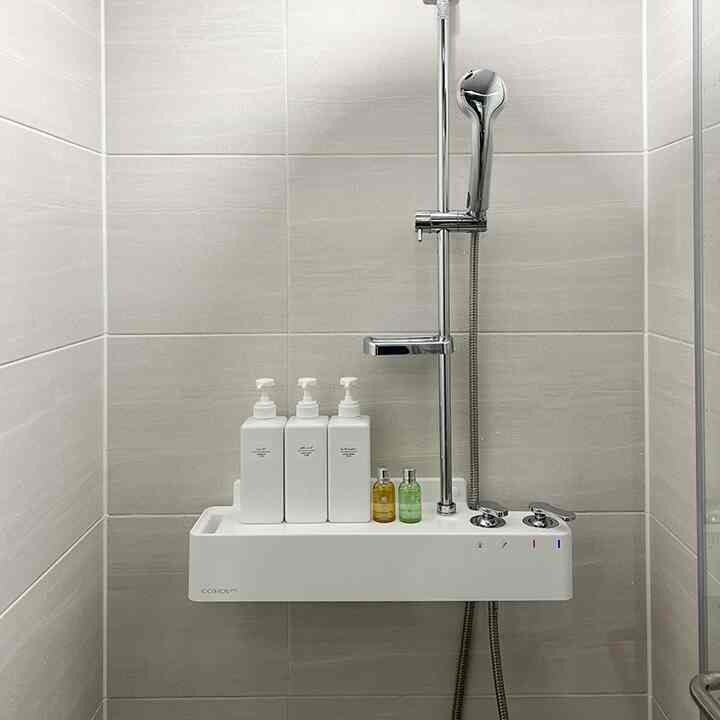 グレーのタイル壁と白い浴室棚、シャワー設備が配置された清潔感のあるバスルーム