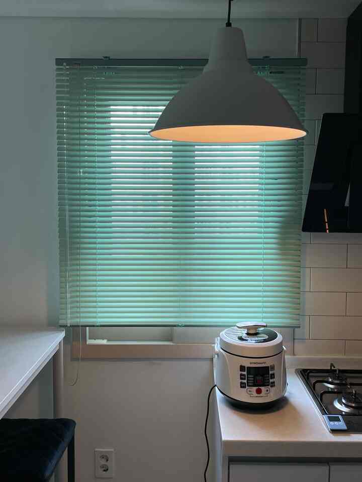 緑色のブラインドと白いキッチンカウンター、レトロな家電があるミニマルなキッチンスペース