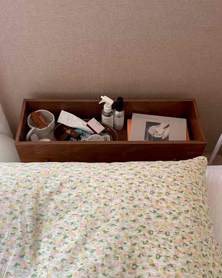 ブラウンの木製プラントボックスがベッド脇に設置された寝室、枕と多彩な小物が整理されている印象的なインテリア