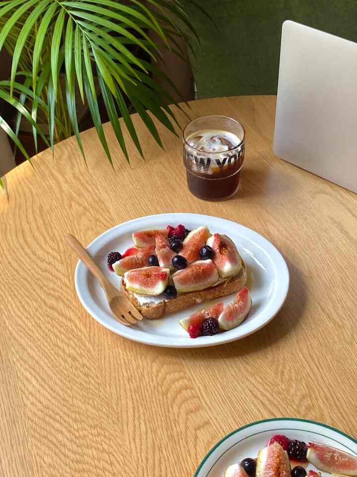 ナチュラルトーンの円形テーブルにブランチの皿とコーヒーが置かれた、落ち着いたおうちカフェの空間