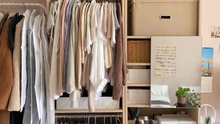 ベージュとナチュラルカラーのクローゼット空間、整頓された洋服と収納ボックスが配置された雰囲気のあるインテリア