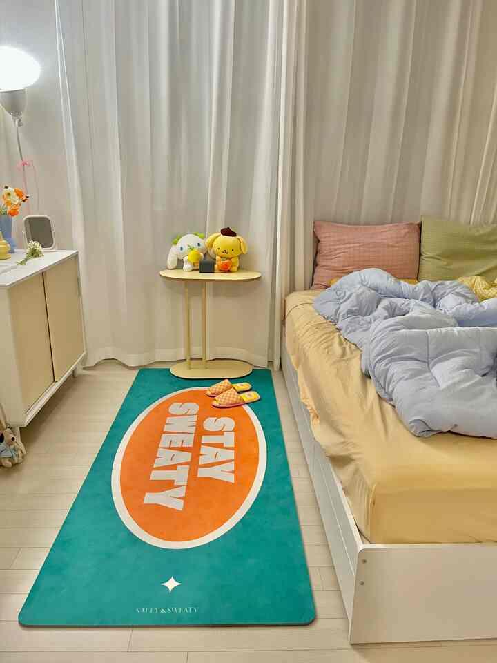 ベージュとパステルカラーが調和したコンパクトな寝室、ベッドとラグ、カーテンが配置された落ち着いた雰囲気のインテリア