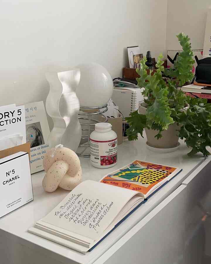 白いキャビネットの上に飾り物と緑の植物が配置されたミニマルなインテリア空間