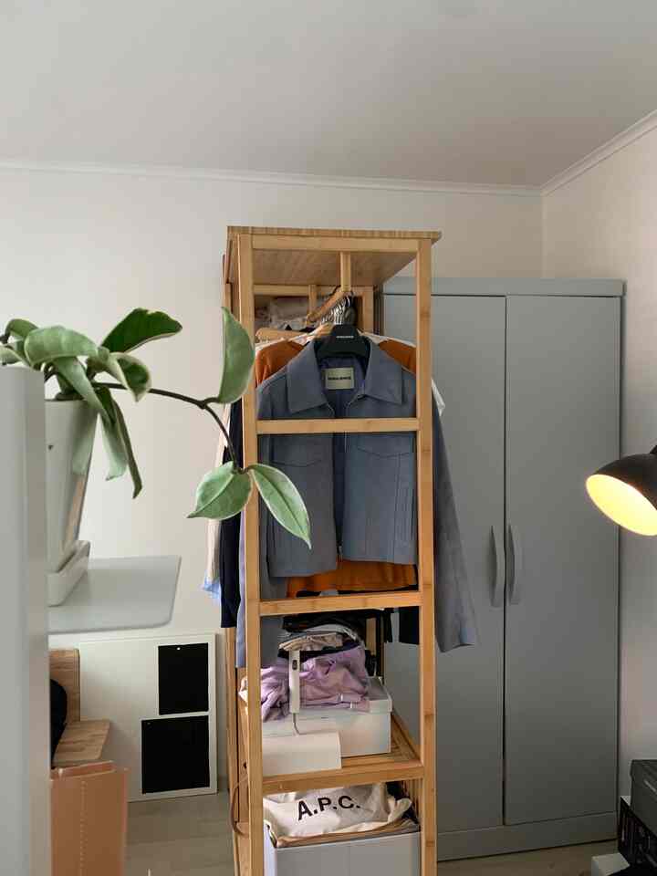 ナチュラルな木目調のラックとグレーのワードローブが配置された印象的な収納空間