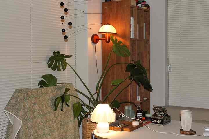 ナチュラルトーンのリビングルーム、木製家具とモビール、壁ランプが配置された雰囲気のあるインテリア