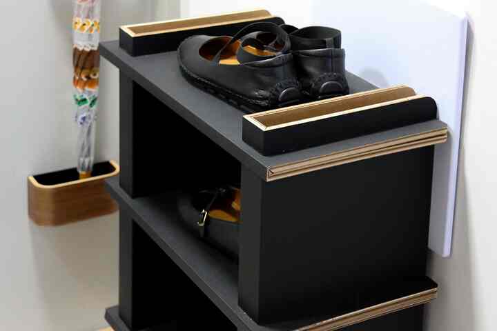 黒いシューズラックと傘立てが壁のそばに置かれた玄関の空間