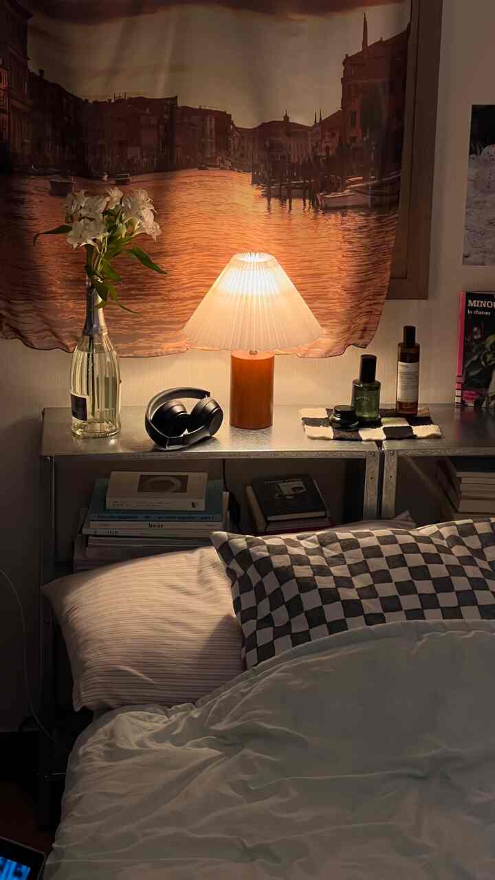 暖かな色調の寝室、チェッカーボードクッションとメタルシェルフ上のテーブルランプが配置された雰囲気のあるインテリア