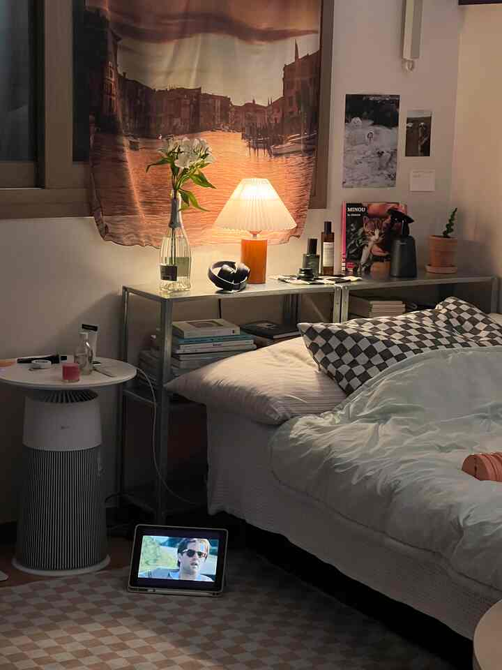 温かみのあるブラウンとホワイトの色調の小さな寝室、チェッカーピローとラグが配置された居心地の良い個人空間