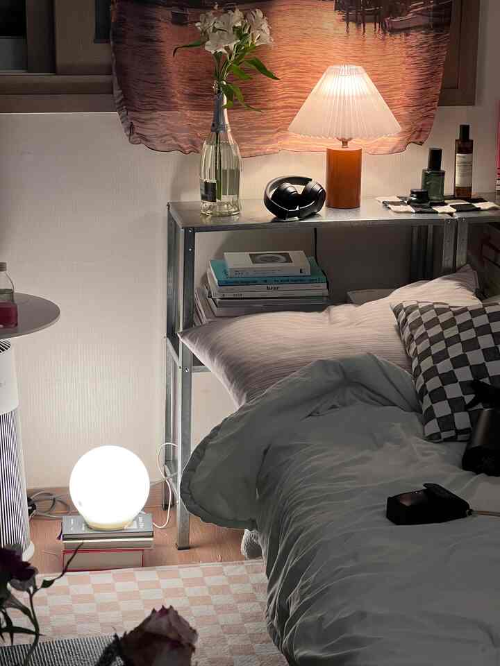 ホワイトとベージュのトーンの小さな寝室、ベッド、テーブルランプ、ラグ、ヘッドホンが配置されたモダンでナチュラルなインテリア