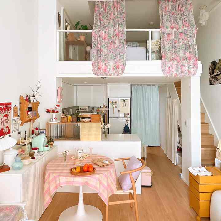 白とナチュラルウッドトーンのワンルームキッチン兼ダイニング、ヴィンテージの花柄カーテンとホームカフェ用品が配置された雰囲気のあるインテリア