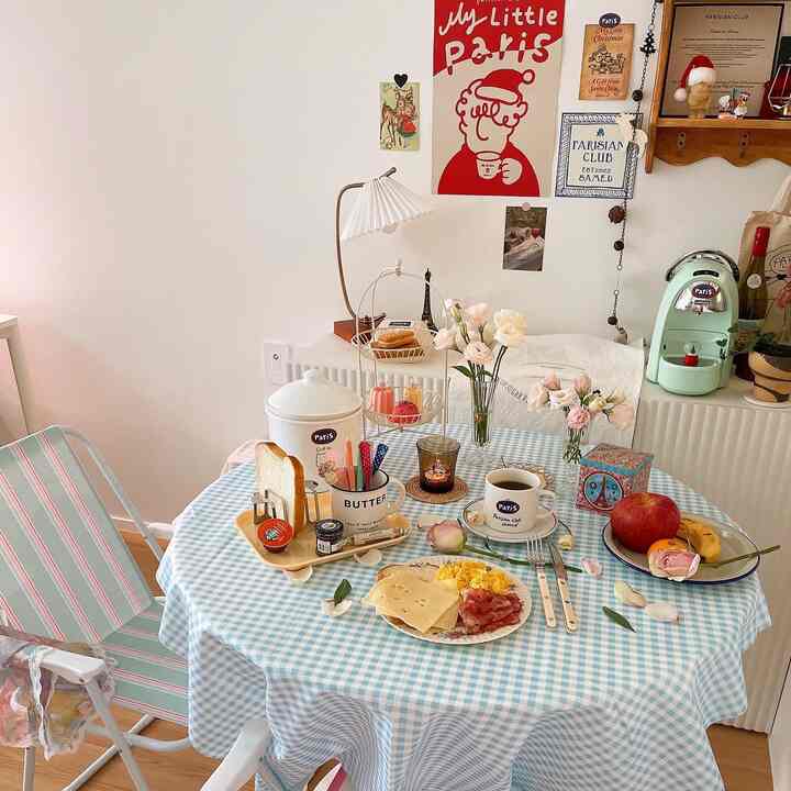 パステルトーンのブルーチェックのテーブルクロスが敷かれたダイニング空間、ホームカフェの小物と花で爽やかな雰囲気のあるインテリア