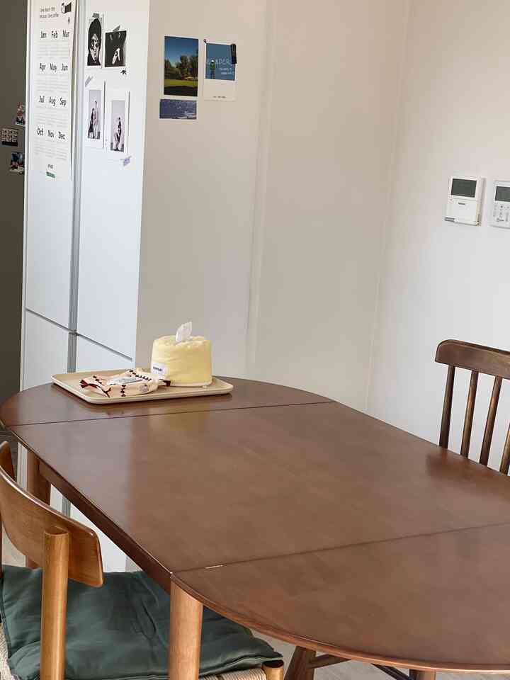 白い壁とブラウンの木目調ダイニングテーブルが配置されたリビング兼ダイニングスペース、自然でシンプルな雰囲気のあるインテリア