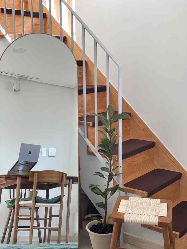 明るいホワイトと温かみのある木目調の空間、階段と全身鏡、木製ダイニングテーブルと椅子が配置された自然な雰囲気の住宅インテリア