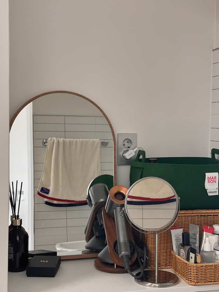 ホワイトとナチュラルカラーが調和した分離型トイレスペース、卓上鏡やドライヤーが整然と配置された印象的な空間