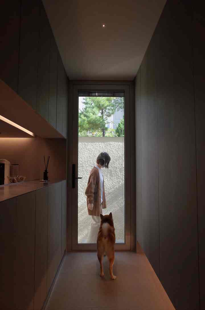 ナチュラルな色調の玄関、ガラス扉と木目調の収納が配置された落ち着いた印象の空間