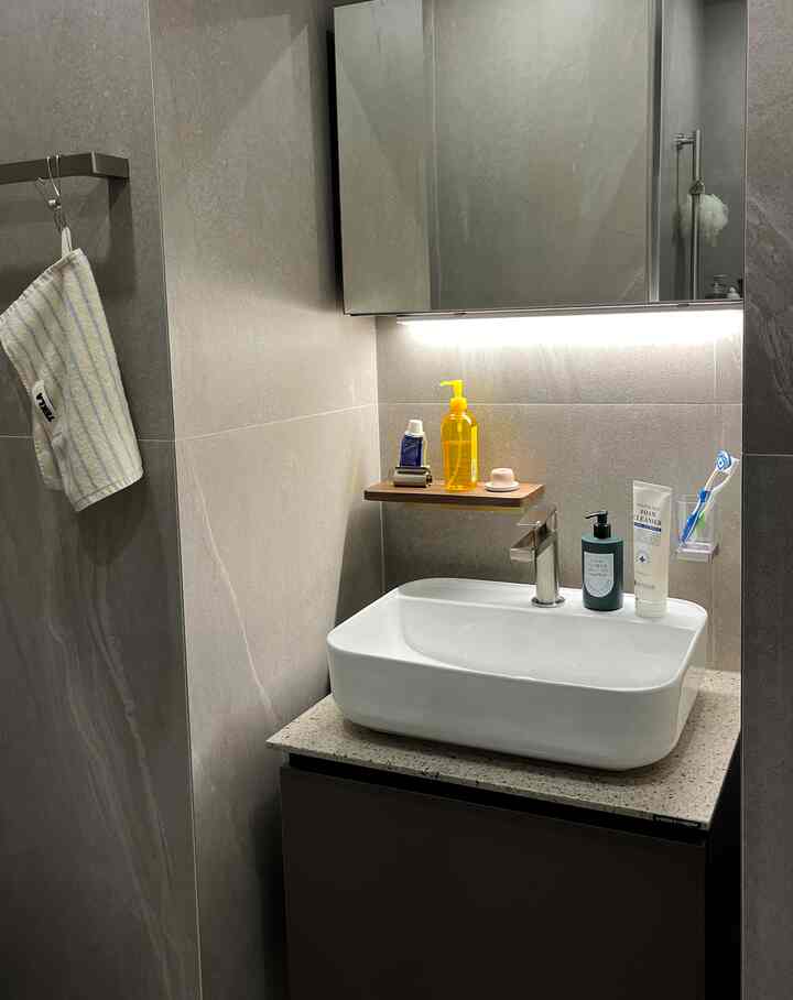 グレーの壁と木製棚が特徴のモダンなバスルームの洗面スペース