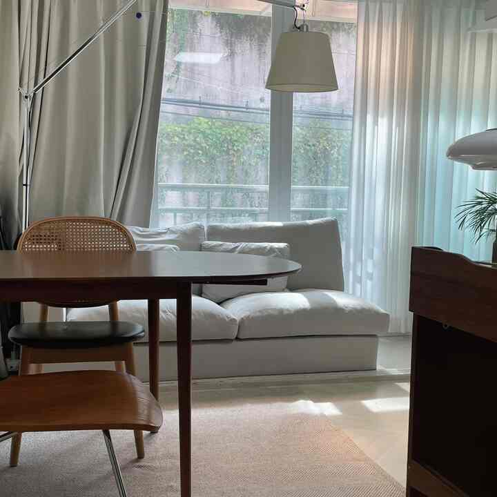 白と木目調が調和したリビング兼ワークスペース、ソファと折りたたみテーブルが配置された雰囲気のある空間