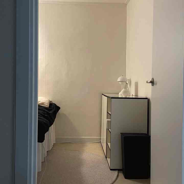 白と黒の色調のシンプルな寝室、右側にキャビネット、左側にベッドが配置された空間