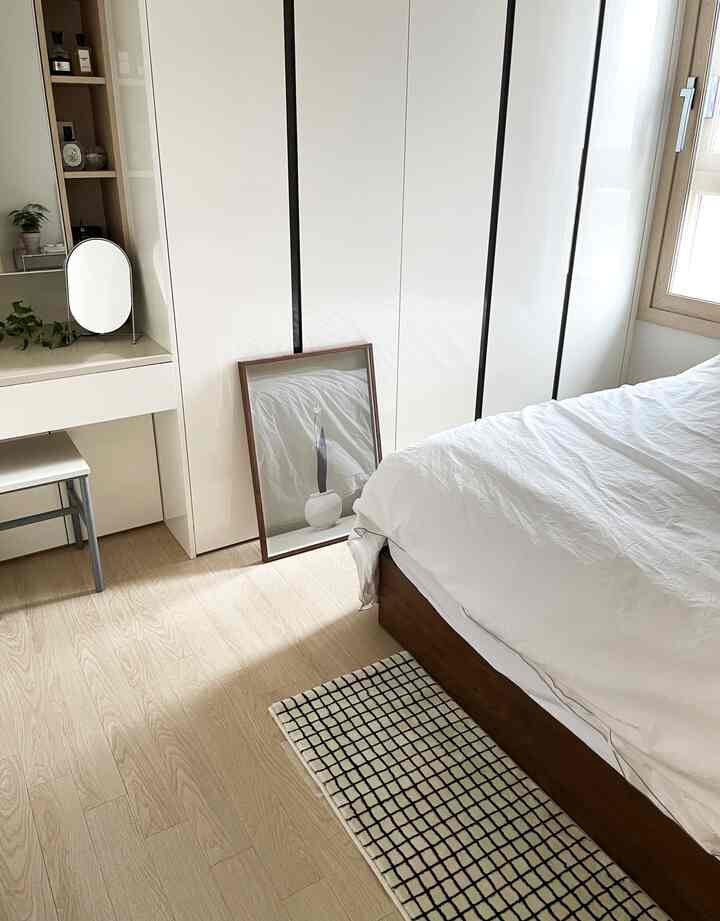 ホワイトと木目調が調和した寝室、整ったベッドと化粧台が配置されたミニマルなインテリア
