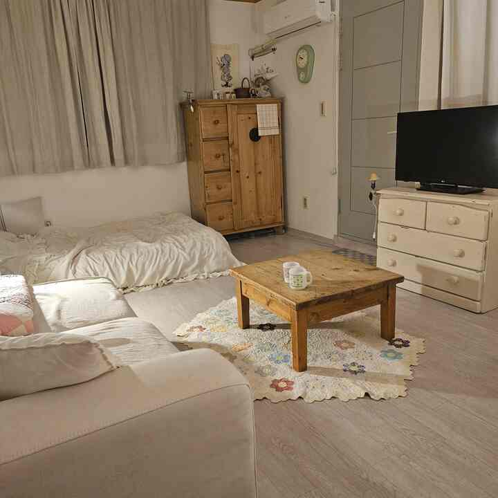 温かみのあるウッドトーンとナチュラルカラーの寝室、低めの木製コーヒーテーブルとベージュのソファが配置された雰囲気のある空間。