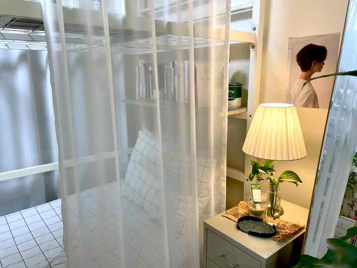 ホワイトとネイビートーンの寝室、透け感のあるシフォンドレープとランプの灯るドレッサーが温かみのある雰囲気を演出する空間