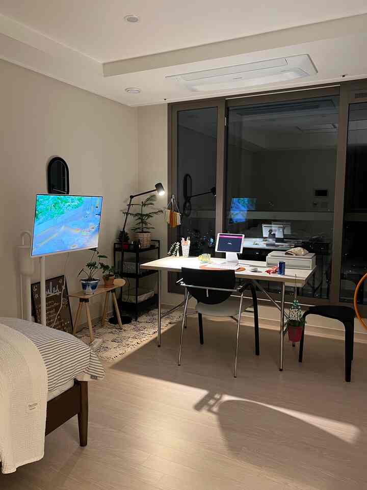 柔らかいベージュの色調のワンルーム寝室兼ホームオフィス空間、机とベッドが配置された整った落ち着きのあるインテリア