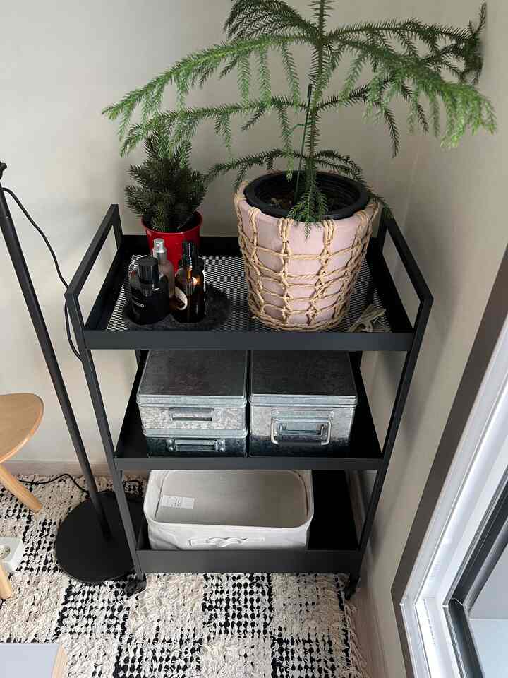 ブラックとホワイトのトーンでまとめられた狭い空間に、金属製トロリーと収納容器が配置されたシンプルなインテリア