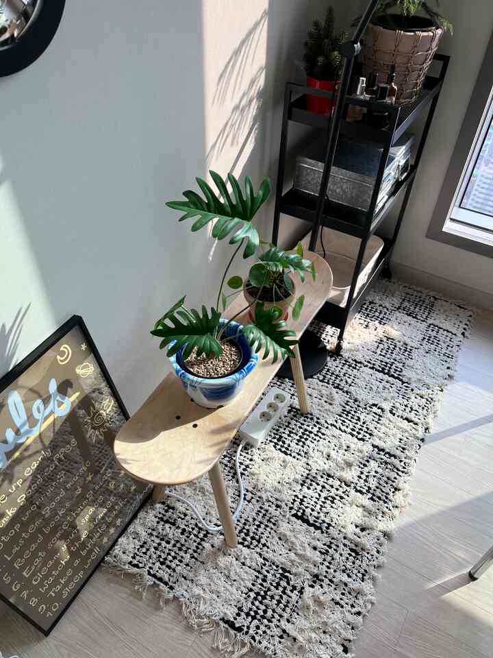 白とナチュラルウッドトーンが調和したホームオフィス空間、スケートボード形状のスツールと植物が置かれた落ち着いたデコと収納のあるインテリア