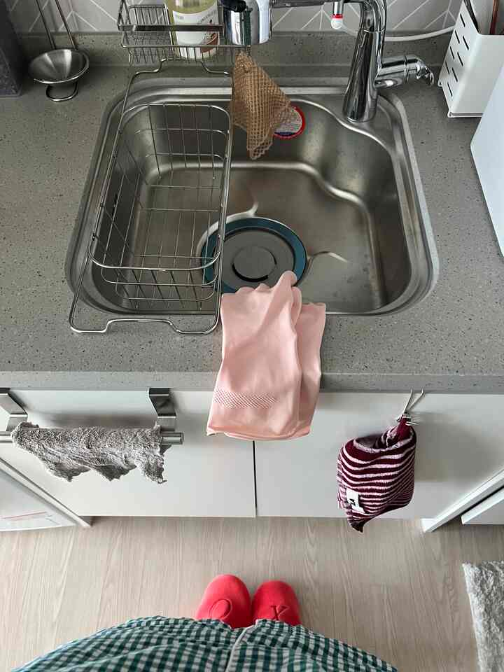 シルバーのステンレスシンクを中央に配し、キッチンタオルとピンクのゴム手袋が掛けられた清潔感のあるキッチンインテリア