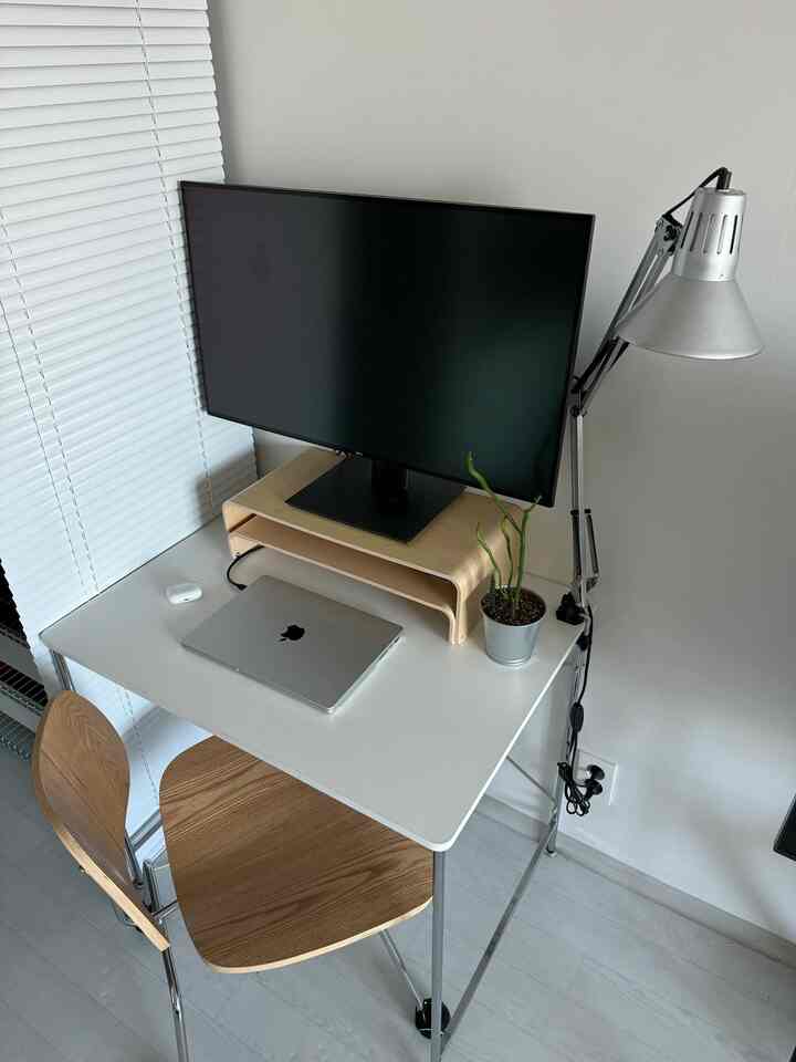 ホワイトと木目調の調和が取れたコンパクトなホームオフィス空間、モニターとデスク、植物が配置されたシンプルモダンなインテリア。