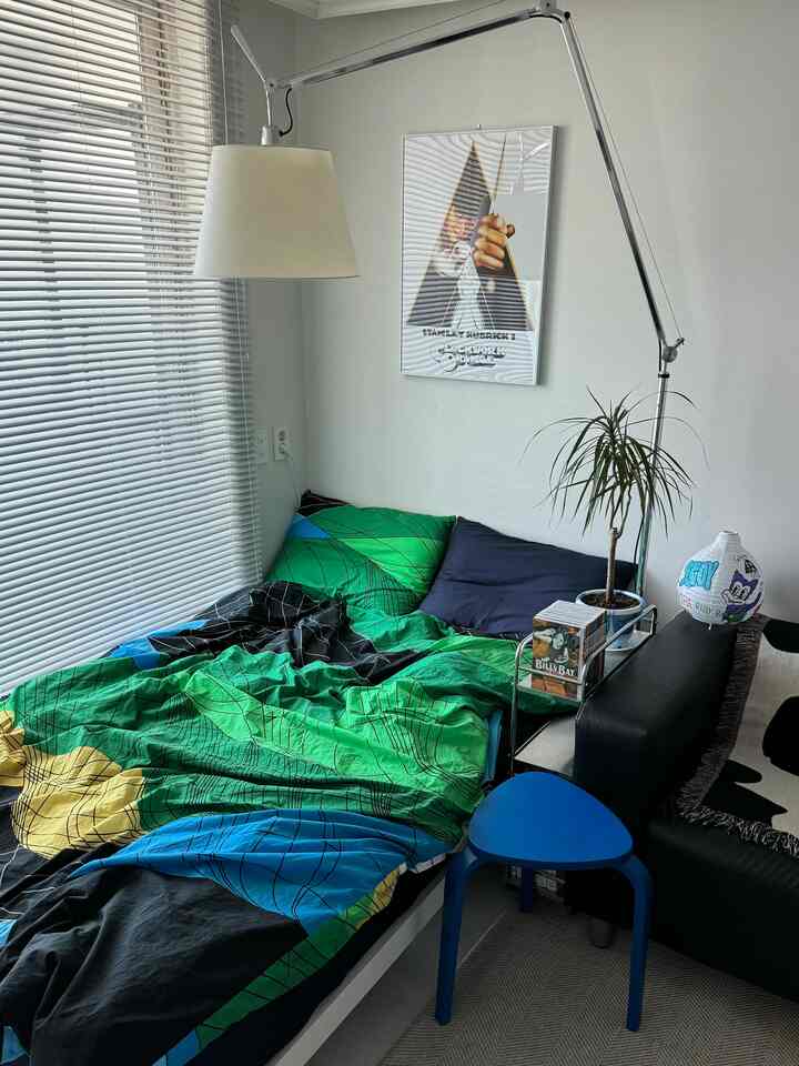 パステル調の寝室、ベッドとソファの間に小さなトロリーが配置された雰囲気のある空間