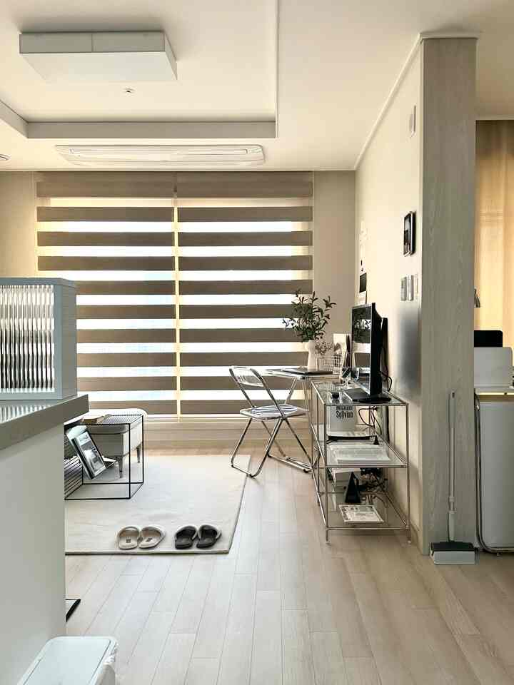 暖かいベージュとホワイトのリビング、透明な椅子とシンプルな家具が調和するナチュラルモダンなインテリア