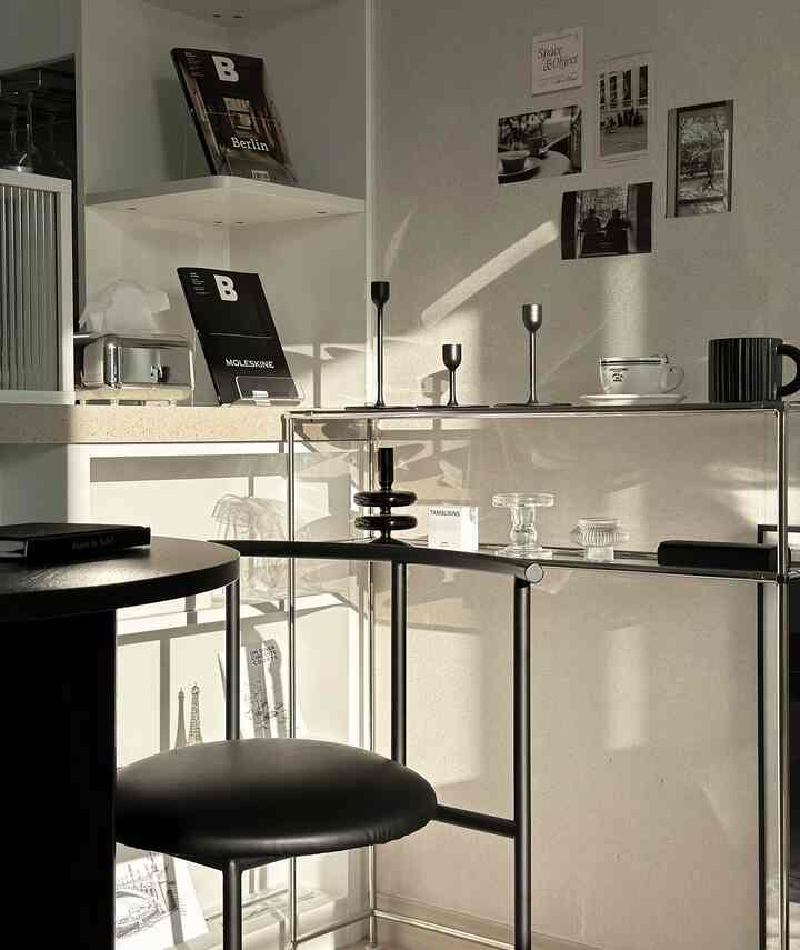 シルバーのコンソールテーブルと黒の丸テーブル、キャンドルホルダーと壁面ポスターが調和したミニマルなリビングスペース