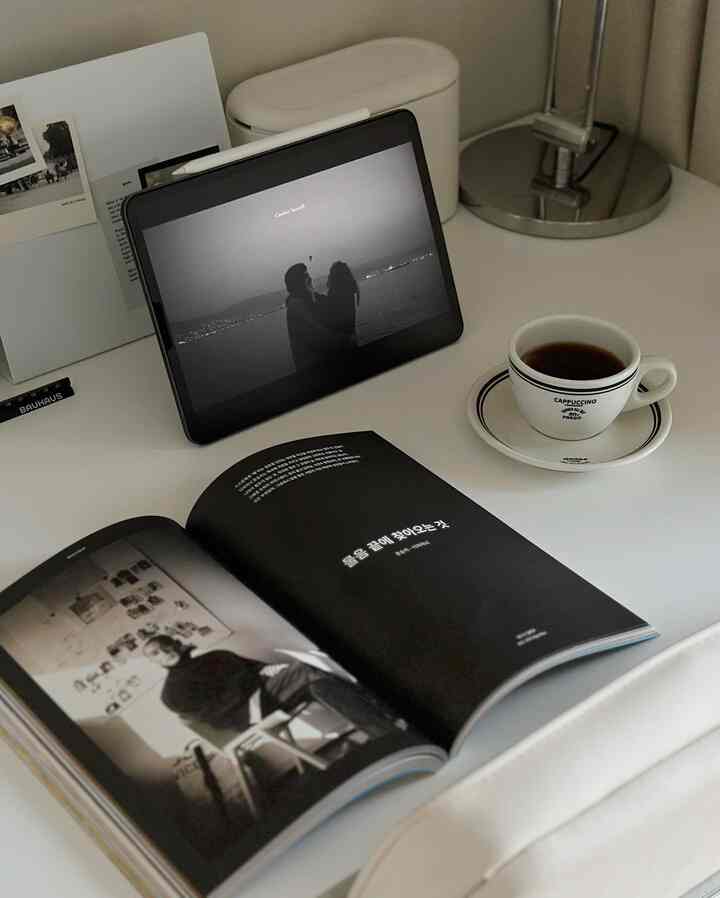 白と黒のトーンのデスクに本とタブレット、コーヒーカップが配置されたミニマルな読書空間