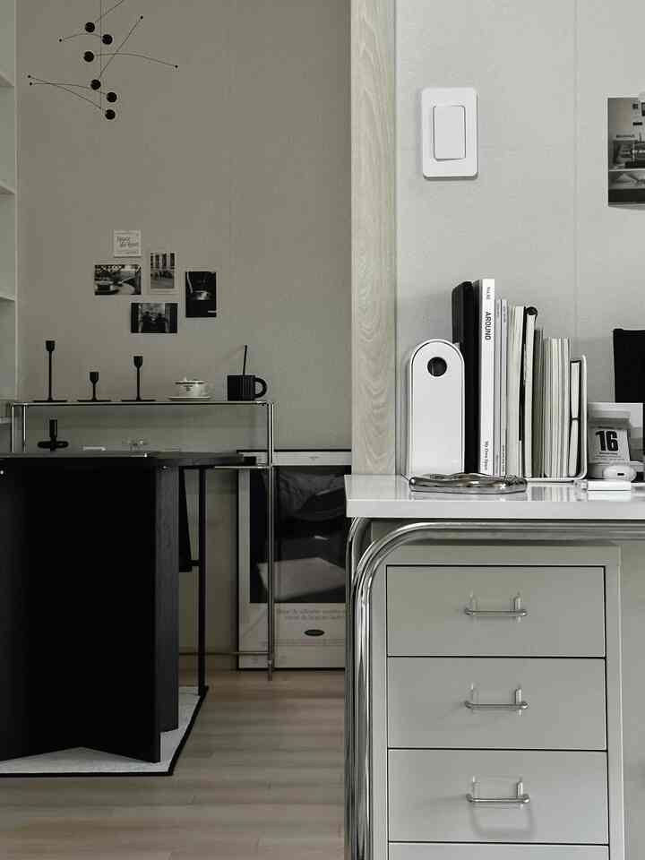 白とグレーのトーンが調和したモダンな書斎、引き出し収納と机上に整理された本と小物が配置された雰囲気のあるインテリア