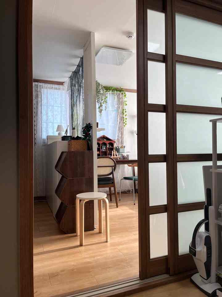 白と木目調の玄関、引き戸と隙間収納、植物とテーブルチェアが配置された自然な雰囲気のインテリア