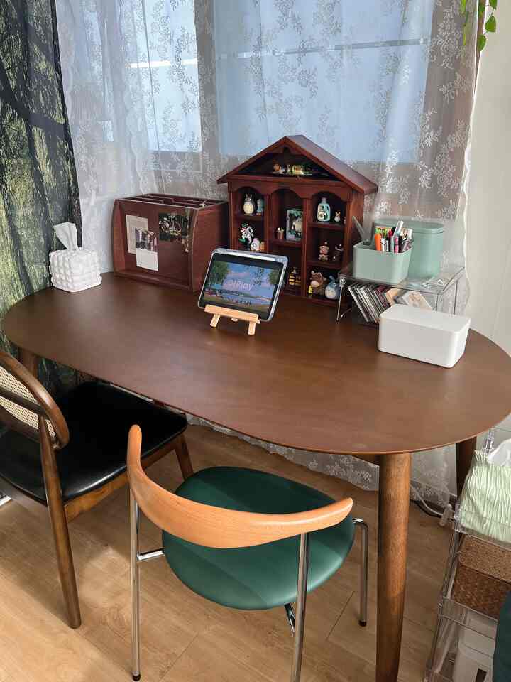 ウッドトーンのナチュラルなホームオフィス兼ダイニングスペース、大きなデスクと小物が並ぶ棚が配置された雰囲気のあるインテリア