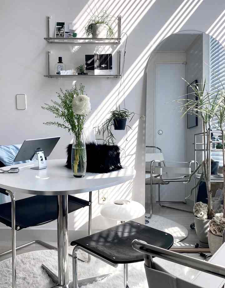 白と黒のトーンのリビング、丸テーブルとブラインドの光が調和した自然でミニマルな雰囲気のインテリア