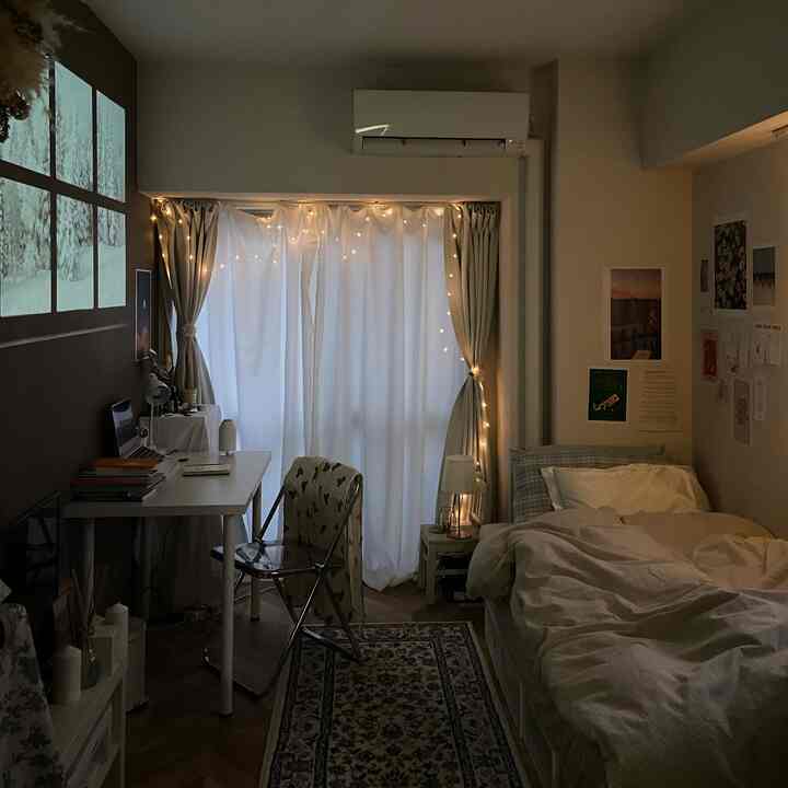 白とベージュのトーンの1Kの小さな部屋、ベッドとデスク、プロジェクターの映像が配された雰囲気のあるインテリア