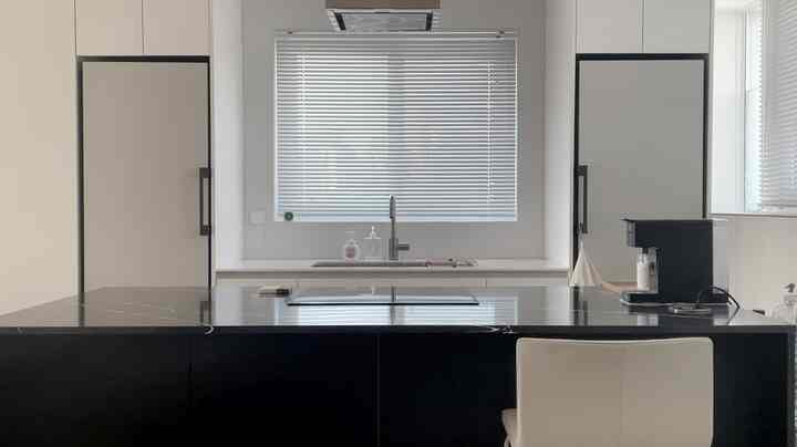 白と黒のトーンでまとめられたキッチン、大きな窓に挟まれたキッチンフィット冷蔵庫、明るく広々とした雰囲気のインテリア