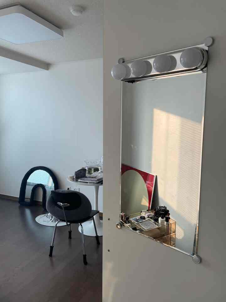 白い壁と木製の床が調和した小さいダイニング空間、鏡と間接照明が配置された清潔感のあるインテリア