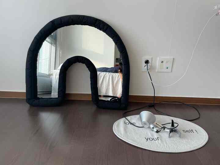 ネイビーとブラウンの色調の寝室、壁に配置されたデザインミラーが空間に抜け感を与える印象的な空間