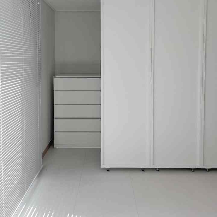 白を基調としたミニウォークインクローゼット、白い間仕切りとチェストが整った雰囲気を生み出す空間